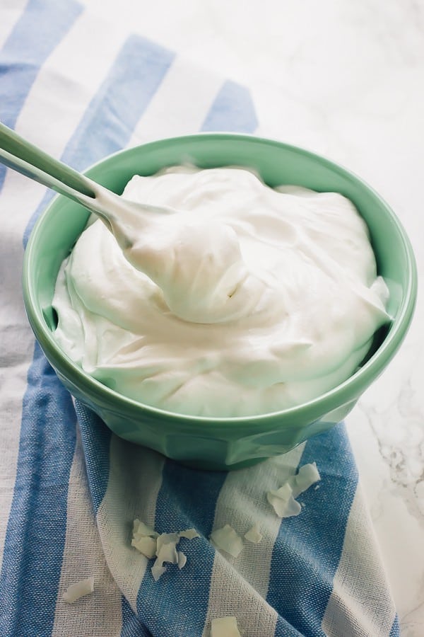 Coconut whipped cream in a blue bowl with a spoon. 