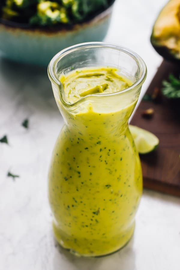 A glass jar with creamy vegan avocado dressing.