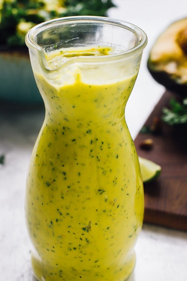 Side on shot of creamy vegan avocado dressing in a glass jar. 
