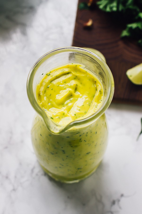 Top down shot of avocado dressing in a glass pouring jar.