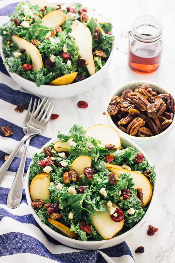 A white bowl of pear, gorgonzola, caramelised pecans with honey apple dressing.