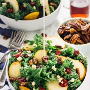 Pear gorgonzola caramelised pecans salad with dressing being poured on.