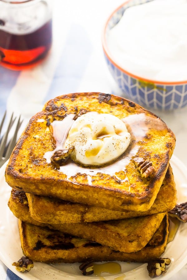 A stack of vegan pumpkin french toast with pecans and cream on top.