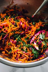 Kale cabbage slaw being mixed in a bowl.