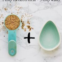 Overhead shot of flax seeds in a blue measuring spoon next to an egg shaped bowl.