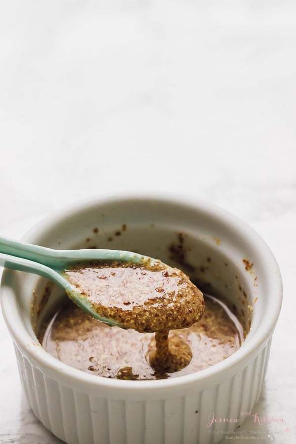 A blue spoon lifting some flax seed mix from a ramekin. 