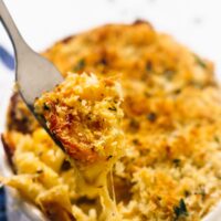 Fork digging into a bowl of baked mac and cheese.