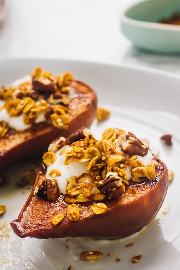 Two vegan cinnamon baked pears with crunchy topping on a white plate.