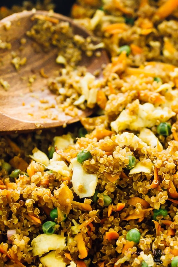 Close up of quinoa fried rice being stirred with a wooden spoon. 