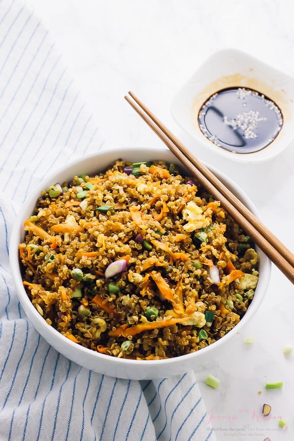 A white bowl of quinoa fried rice with chopsticks.