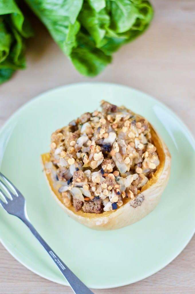 Mushroom and lentil stuffed butternut squash on a blue plate with a fork on the side. 
