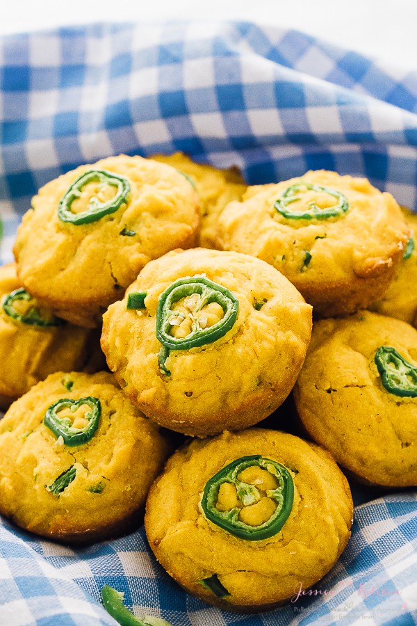 A batch of gluten free cornbread muffins on blue check cloth.