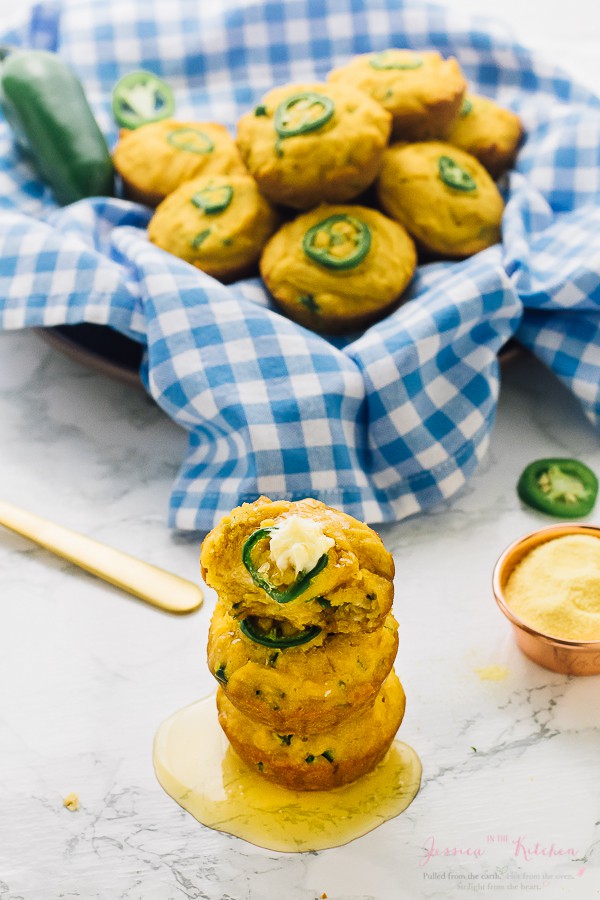 A stack of gluten free cornbread muffins in front of a bowl of corn bread muffins. 