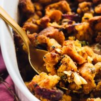 A spoon scooping out some gluten free cornbread stuffing from a casserole dish.