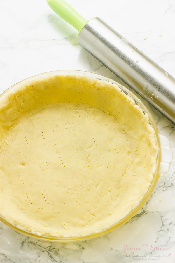 Gluten-free vegan pie crust in glass pie plate with rolling pin in background