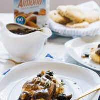 Vegan mushroom gravy on top of biscuits with a carton of almond milk in the background.