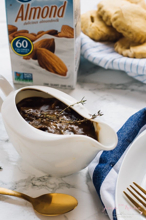 Gravy boat full of vegan mushroom gravy with a carton of almond milk in the background. 