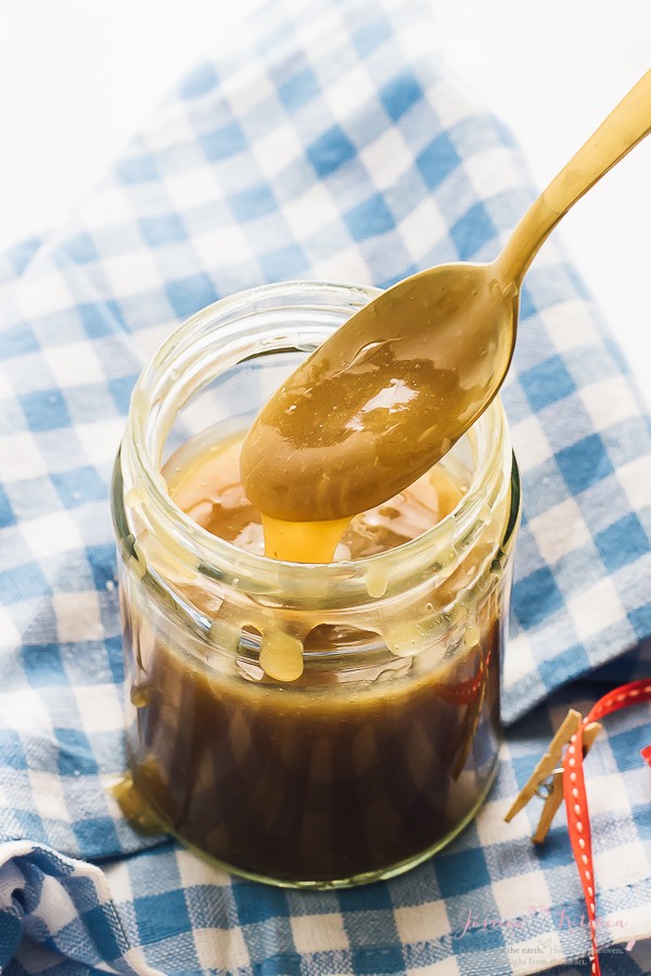 Vegane Karamellsauce im Glas mit Löffel zum Eingießen.