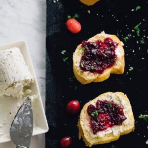 Top down shot of cranberry goat crostini on a black slate with cranberries.