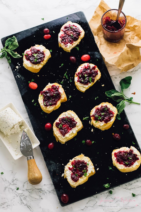 Overhead shot of crostini on a black slate with cranberries. 