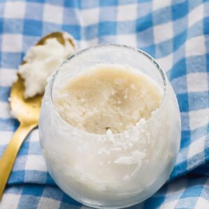 Overhead shot of coconut butter in a glass with a golden spoon on the side.