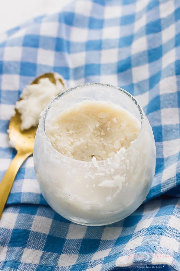 Top down shot of coconut butter in a round glass with a spoon on the side. 