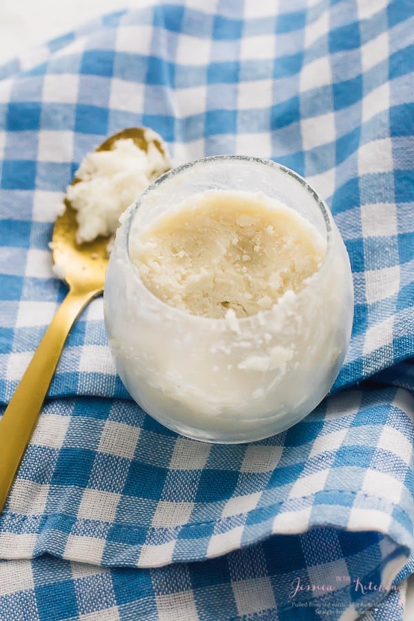 Coconut butter in a round glass with a gold spoon on the side. 