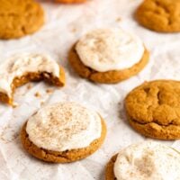 pumpkin cookies with cream cheese frosting on a parchment paper