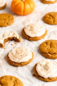 pumpkin cookies with cream cheese frosting on a parchment paper