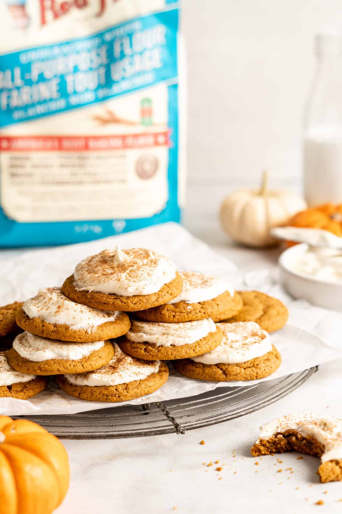 pumpkin cookies with cream cheesefrosting spread on them and stacked