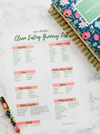 Top down shot of printed clean eating grocery list with pen and notebook on the side.