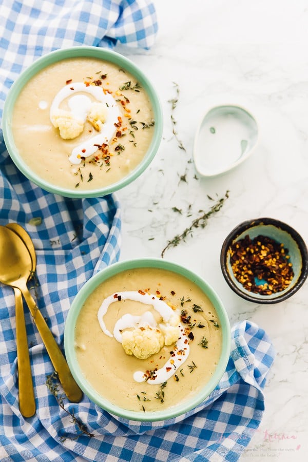 Top down view of cauliflower soup in two blue bowls. 