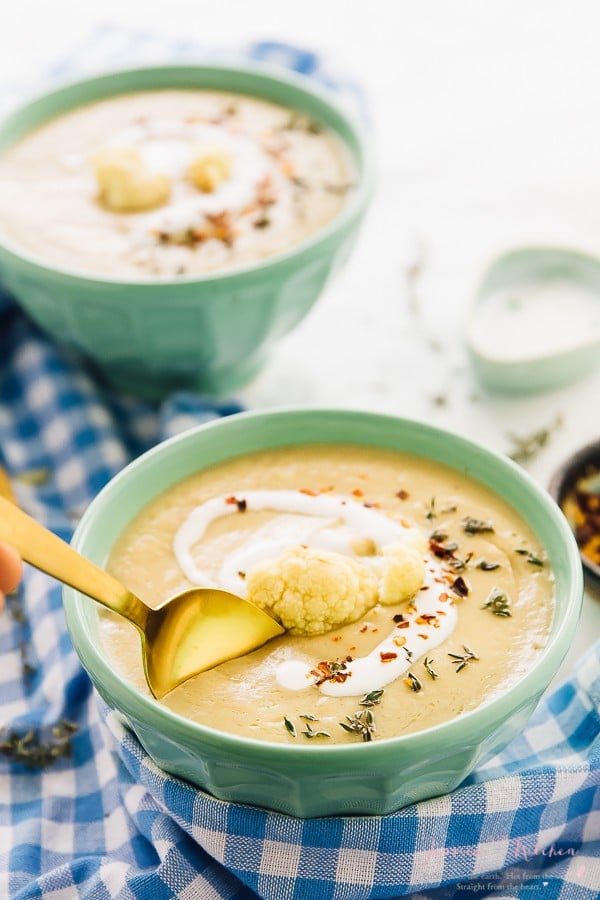 This roasted cauliflower soup with spoon dipped into it. 