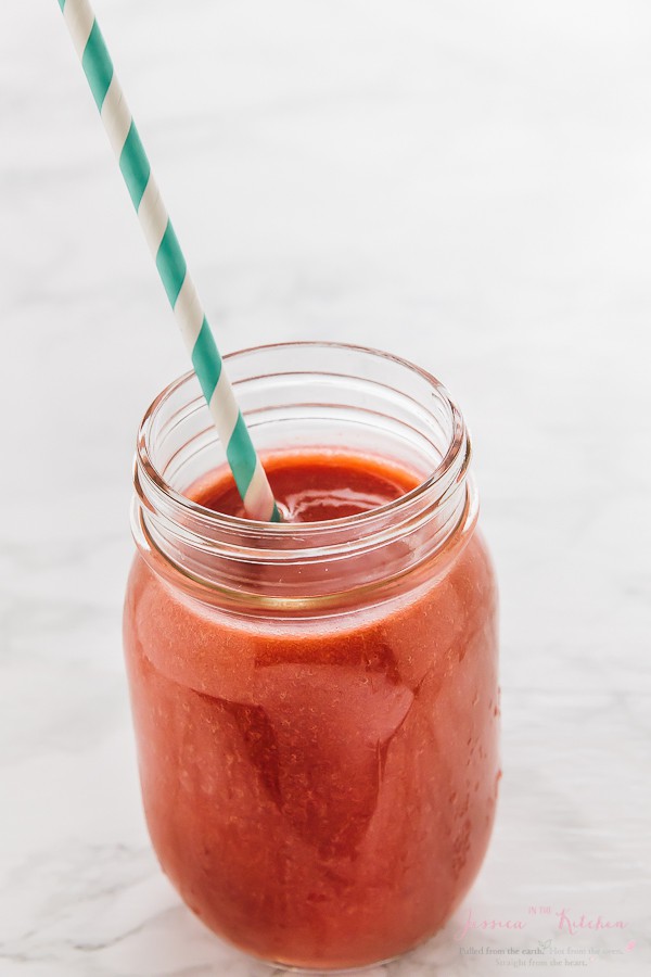 Red smoothie in a mason jar with a straw. 