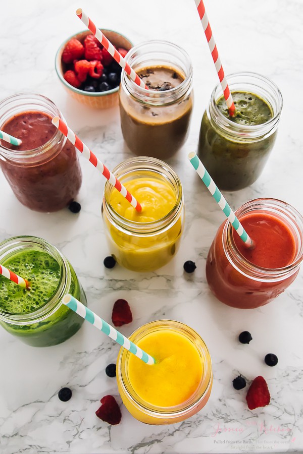 Top down shot of seven banana smoothies on a white table with berries on the side