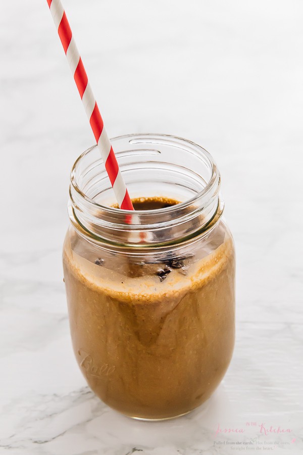 Peanut butter smoothie in a glass mason jar with a straw. 