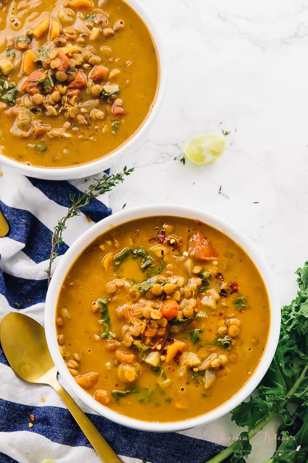 Top down lentil soup in two white bowls with a gold spoon on the side.