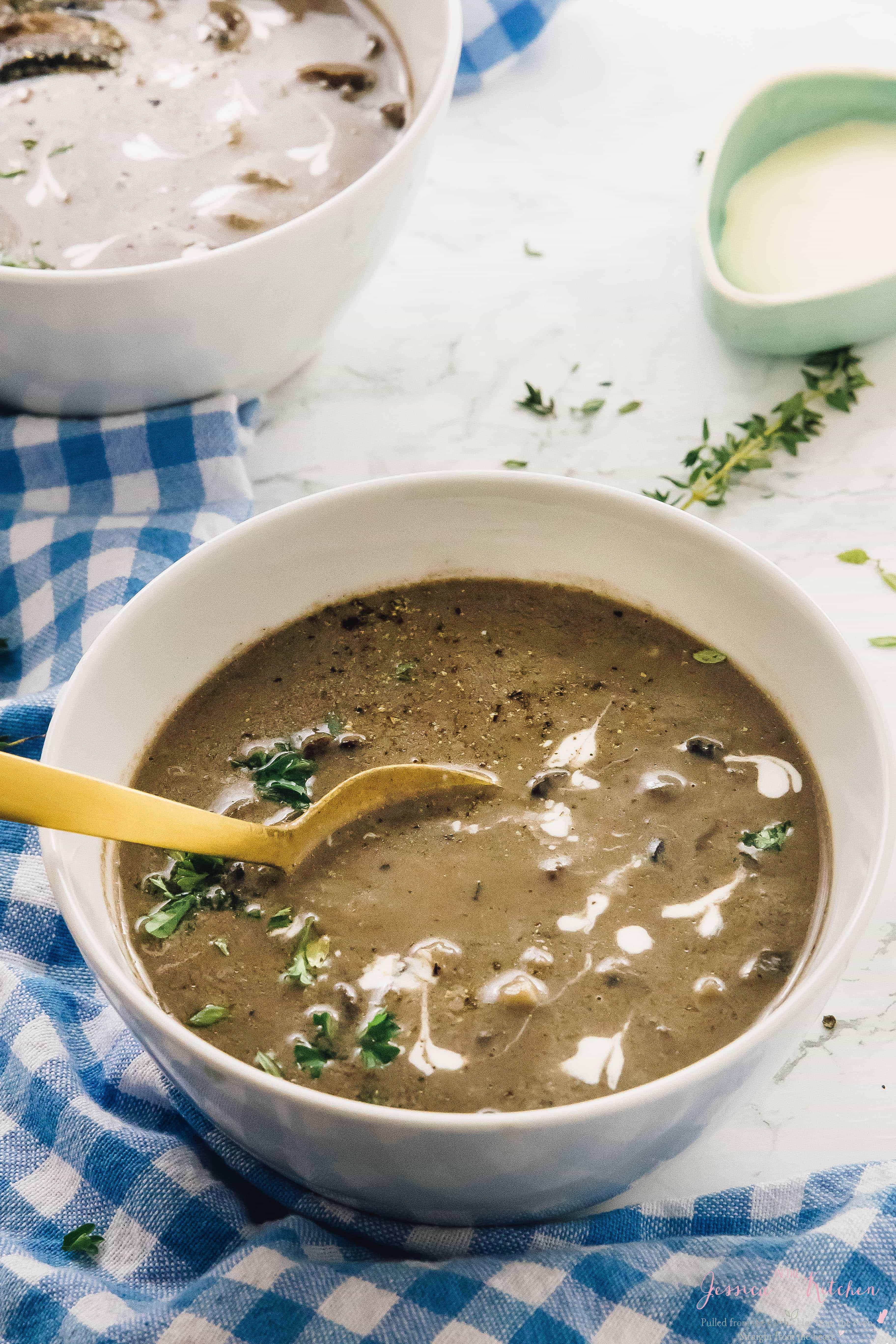Creamy mushroom soup in a white bowl with gold spoon.