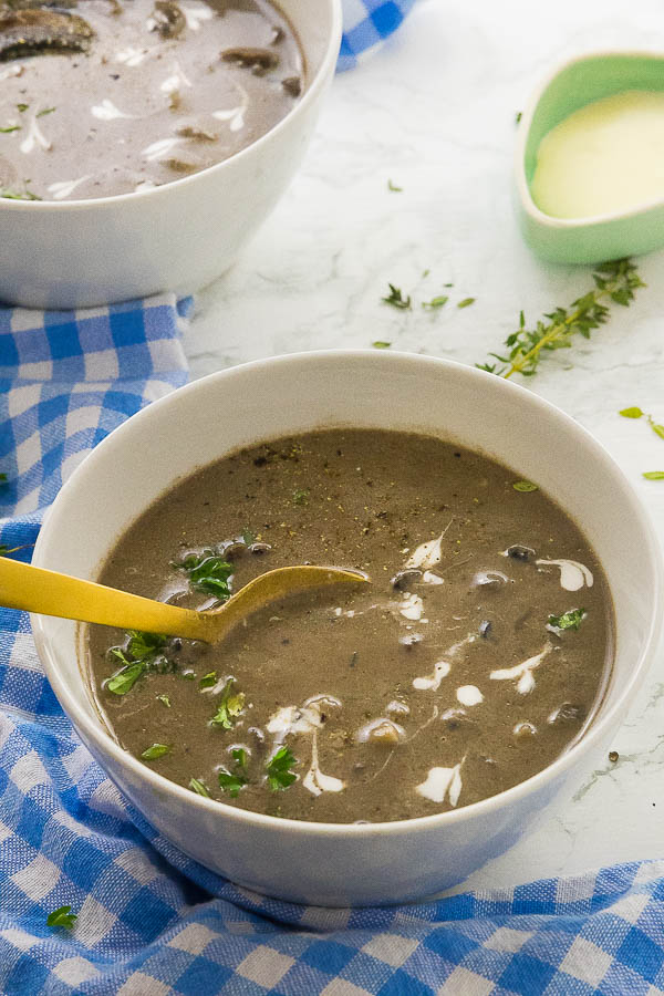 A bowl of creamy mushroom soup, with a spoon dipped in. 