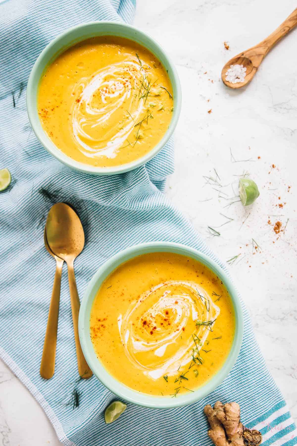 Top down shot of roasted carrot soup in two white bowls.
