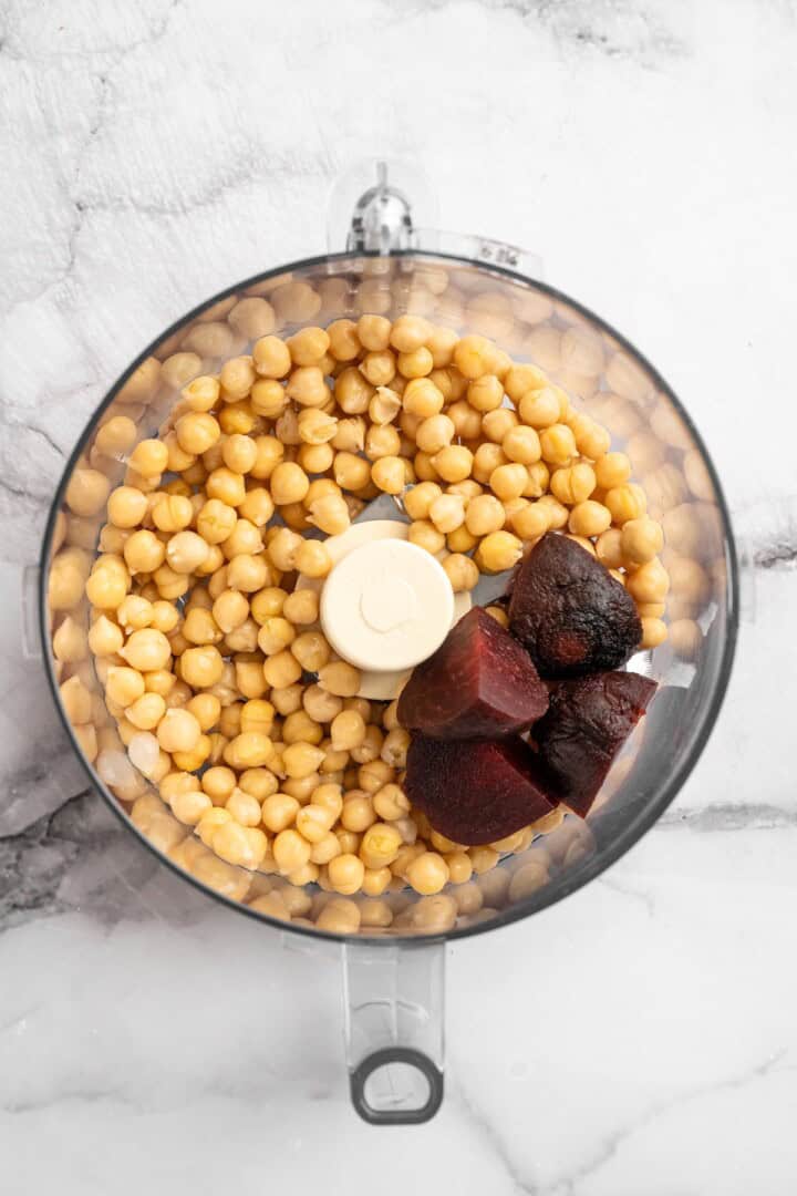 Overhead view of roasted beets and chickpeas in food processor bowl