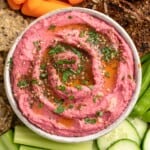 Bowl of beet hummus on platter with crudite and crackers