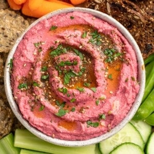 Bowl of beet hummus on platter with crudite and crackers
