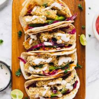 Overhead view of 4 crispy zucchini tacos lined up on a wooden board