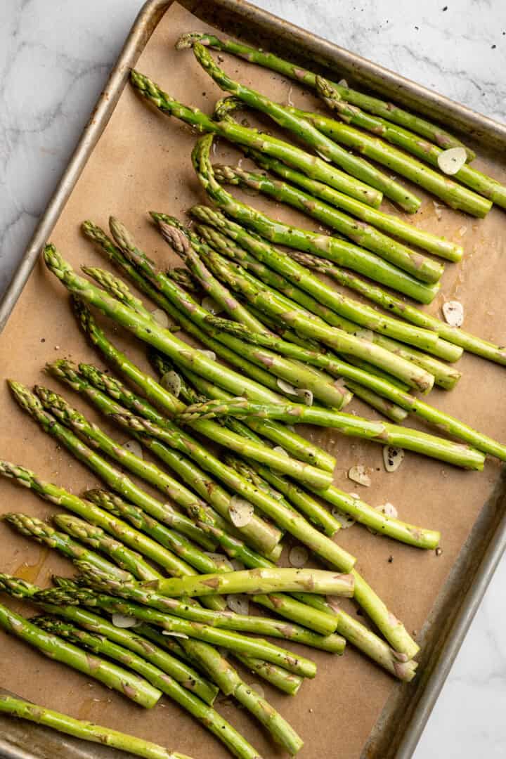 Roasted asparagus on sheet pan with garlic slices.
