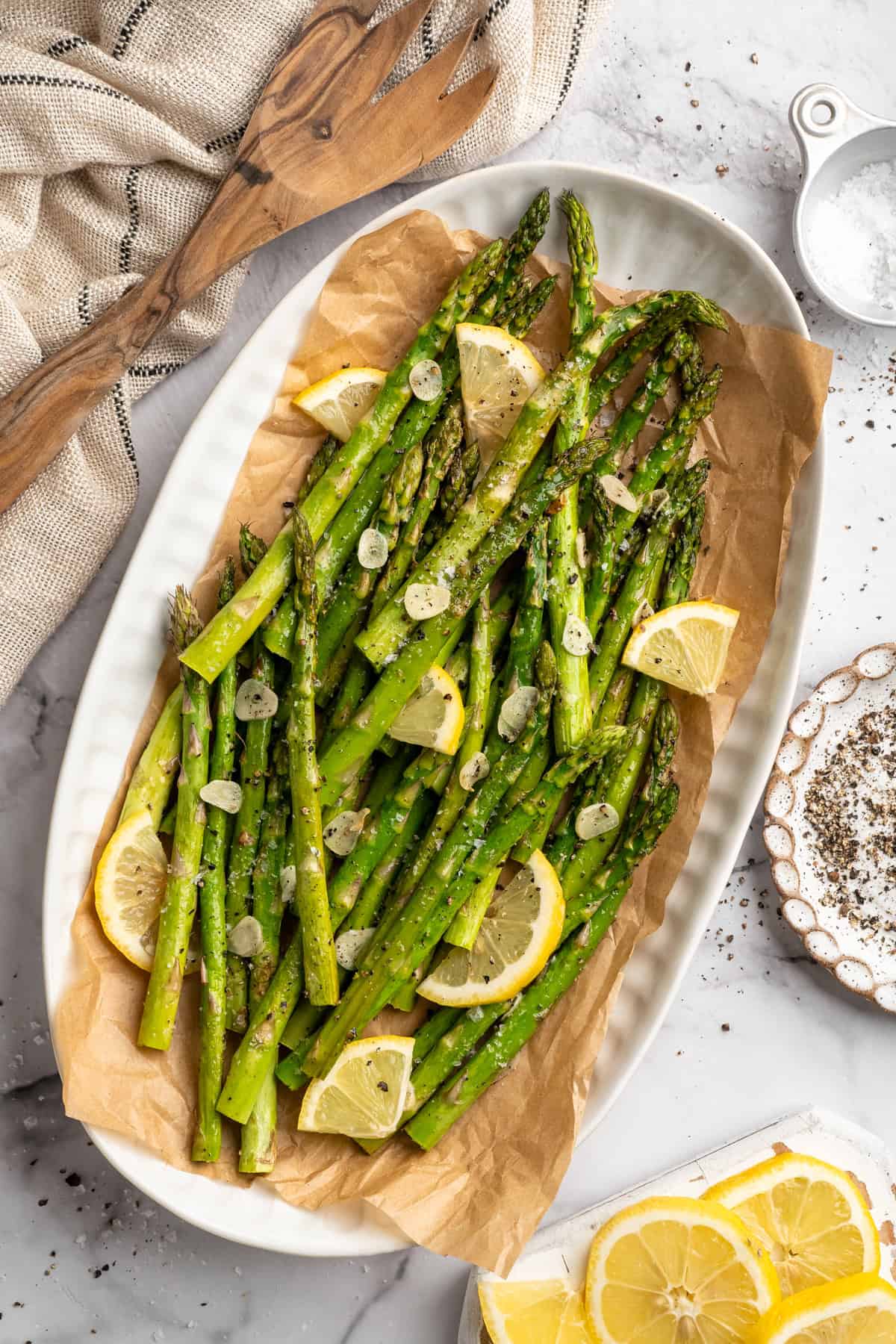 Platter of garlic roasted asparagus with slices of lemon.