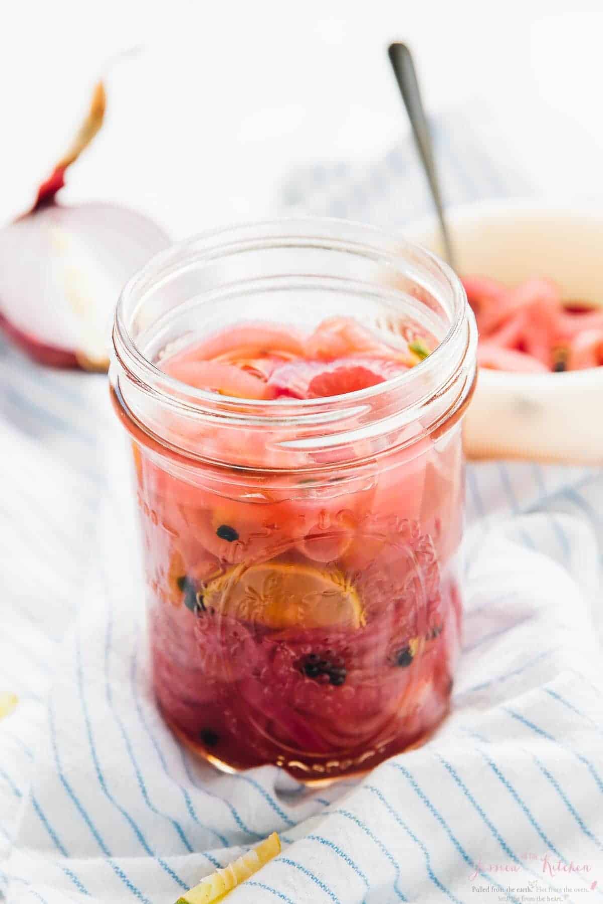 Side on shot of pickled onions in a glass jar.