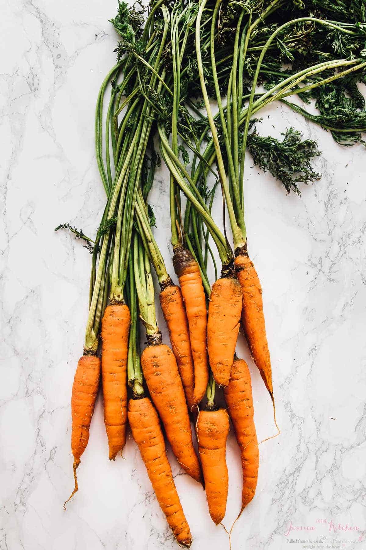 Top down shot of fresh carrots on a white table top. 