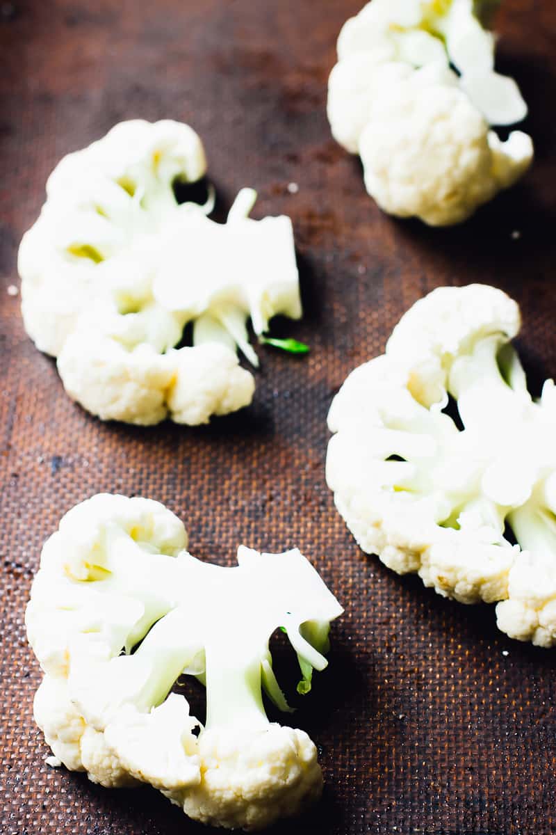 Slices of raw cauliflower florets on a baking sheet. 