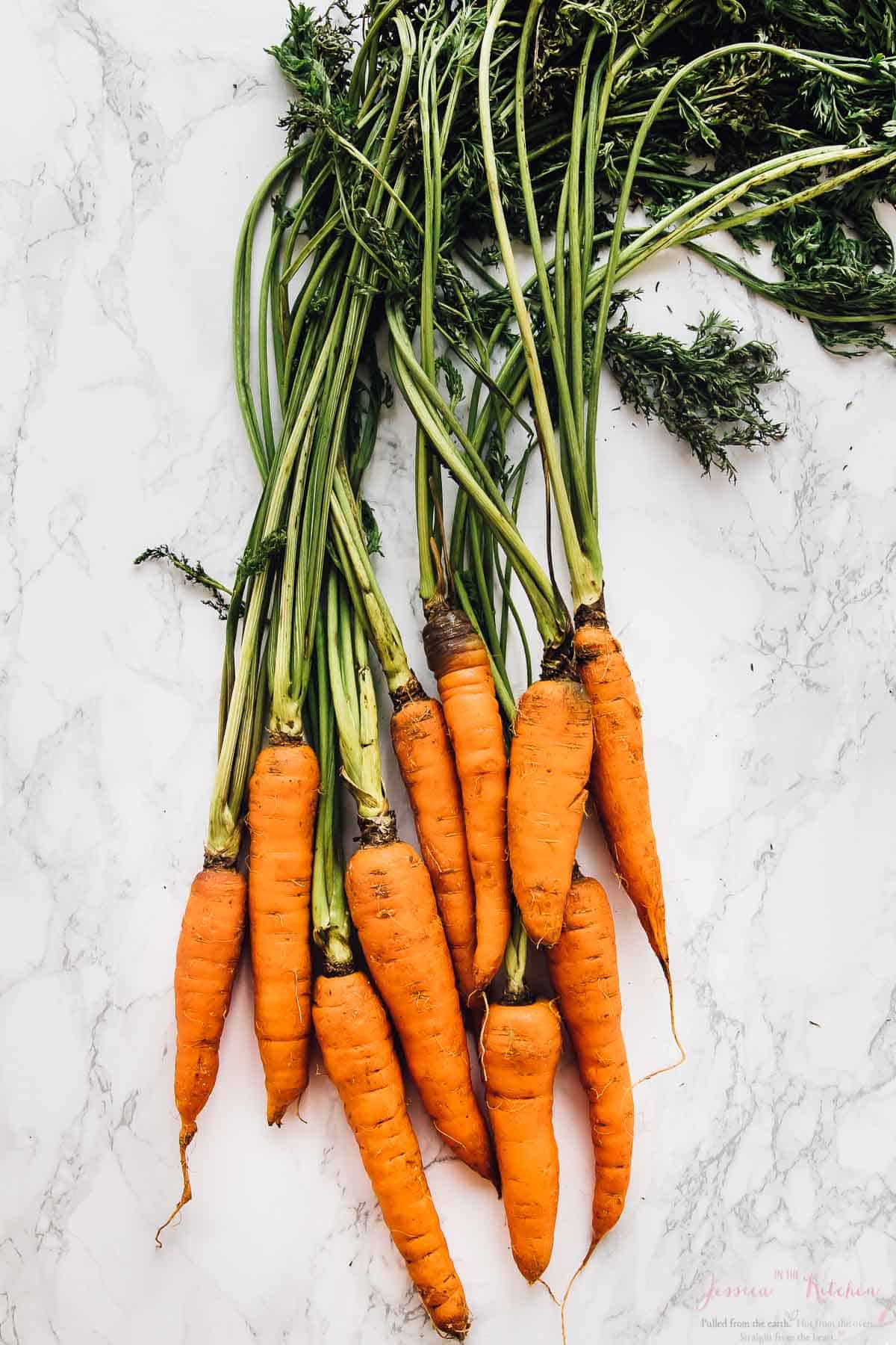 Top down sot of raw carrots on a white table. 